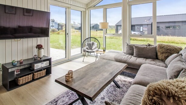 A spacious living room with a large sofa, a coffee table, and a TV mounted on the wall. - "Alea" - 800m from the sea by Interhome (Hjørring)