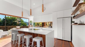 Una cucina moderna con una grande isola, sgabelli da bar bianchi e un frigorifero integrato.
