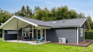Una casa moderna con un porche cubierto, piscina y un amplio ventanal.