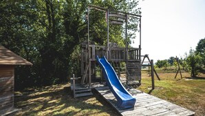 Een speeltuin met een blauwe glijbaan en houten klimconstructies.