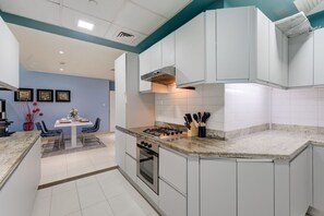 Une cuisine moderne avec des meubles blancs, une cuisinière à gaz et un coin repas comprenant une table et des chaises.