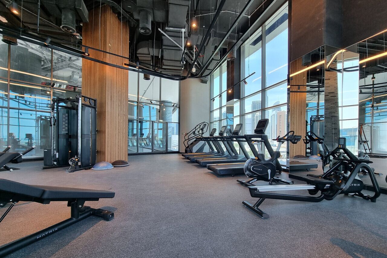 Une salle de sport équipée de tapis de course, d’appareils de musculation et d’un banc.