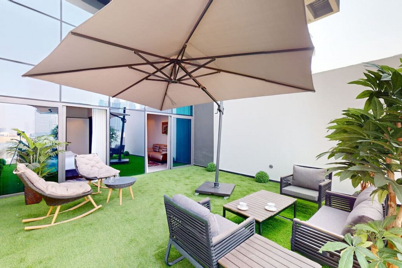 A modern outdoor patio with a swing chair, a cushioned seating area, and a dining table.