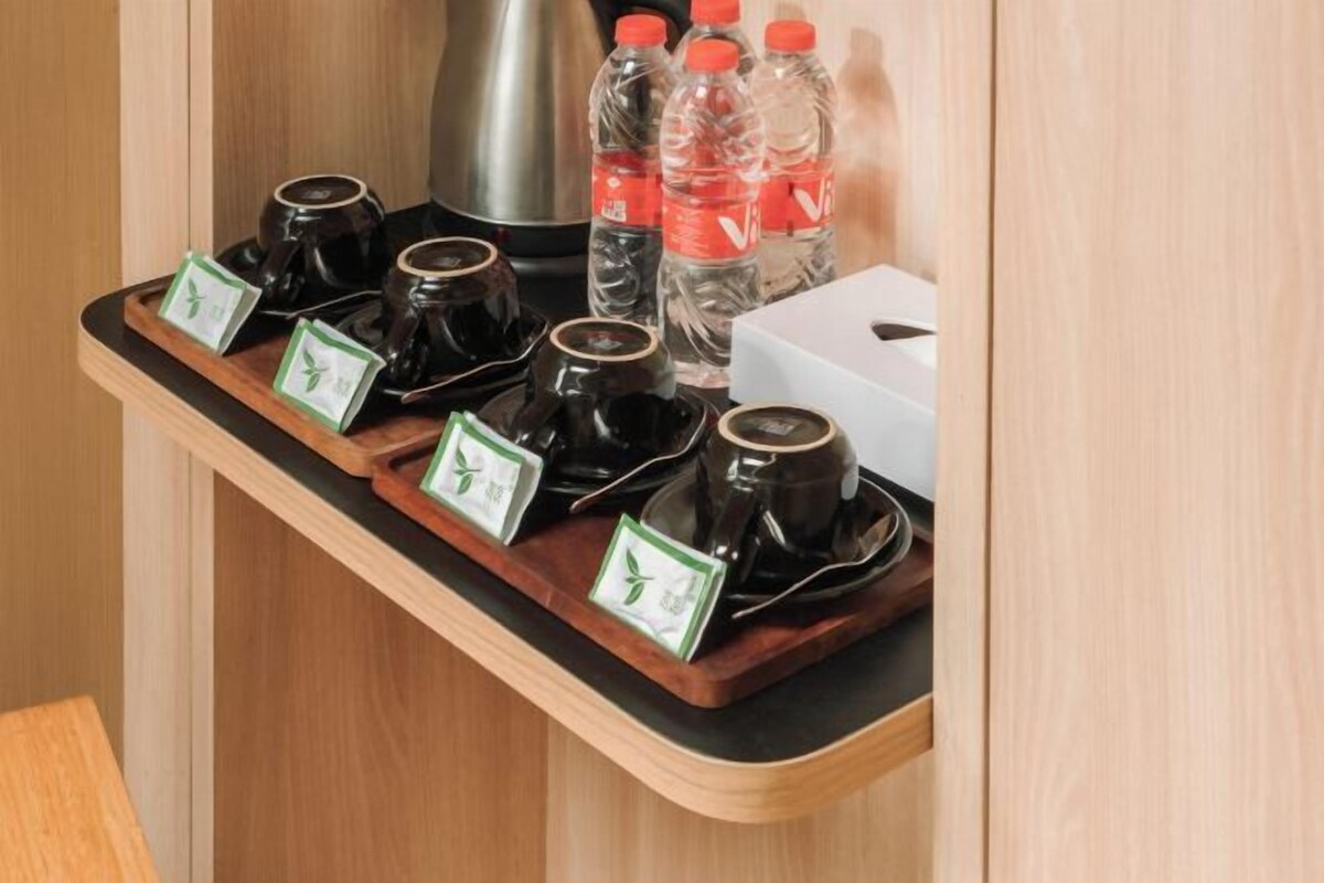Una bandeja con varias tazas de café y un hervidor sobre una encimera de madera.