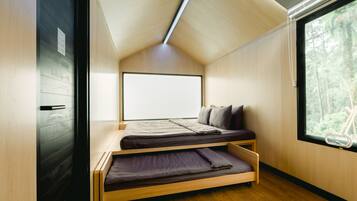 A compact bedroom with a bunk bed, a large window, and a view of the forest.