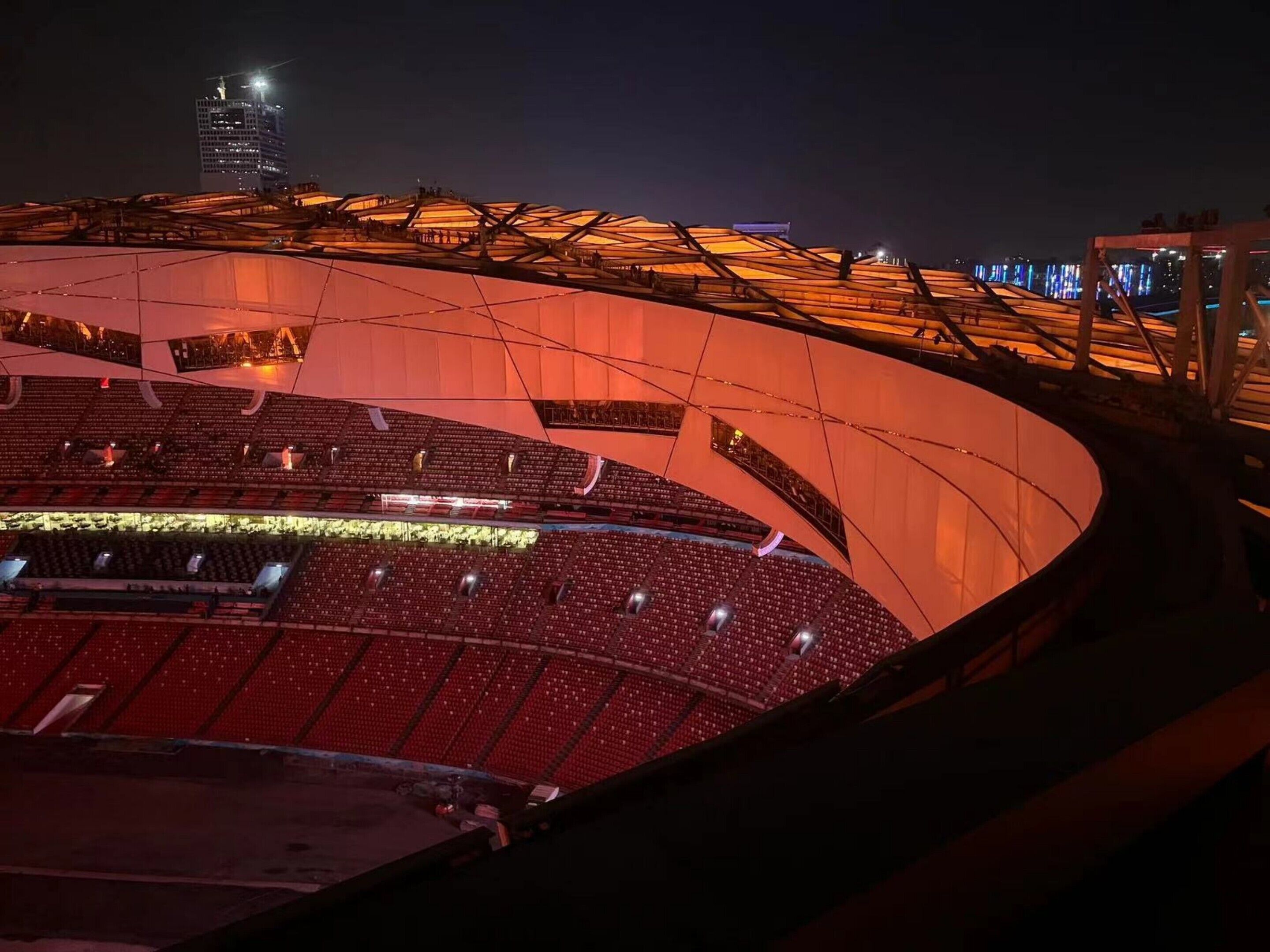 Un estadio grande y moderno con asientos escalonados y una estructura de techo iluminada y destacada.