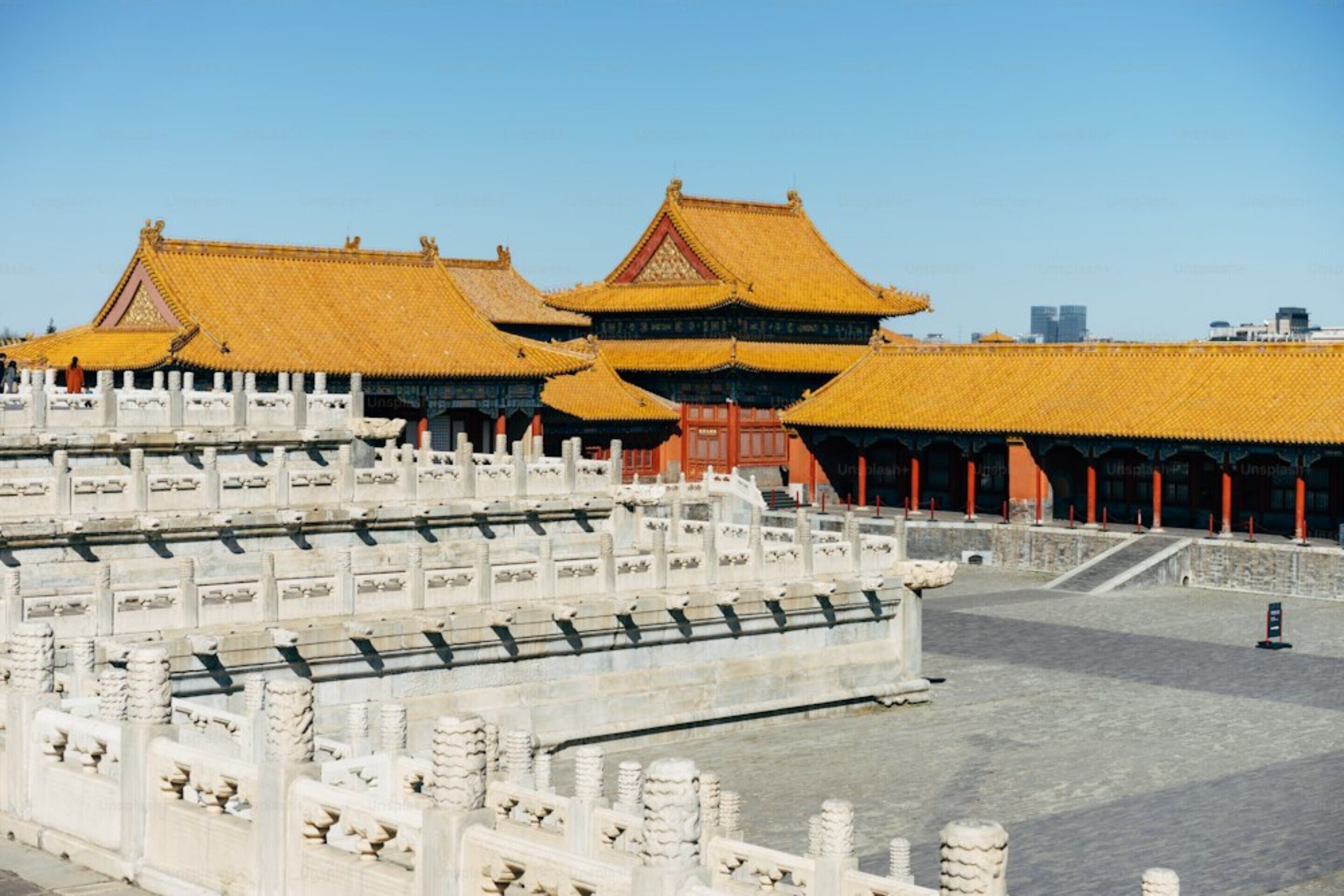 A traditional Chinese architectural complex with multiple buildings featuring yellow tiled roofs and white stone walls.