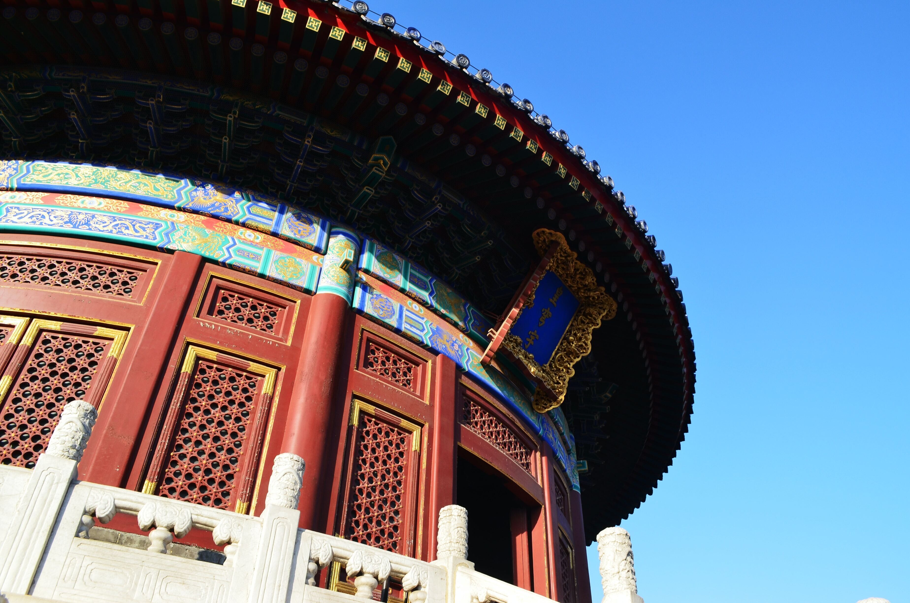 A traditional building with ornate red and blue roof tiles, a large circular structure, and a prominent golden emblem.