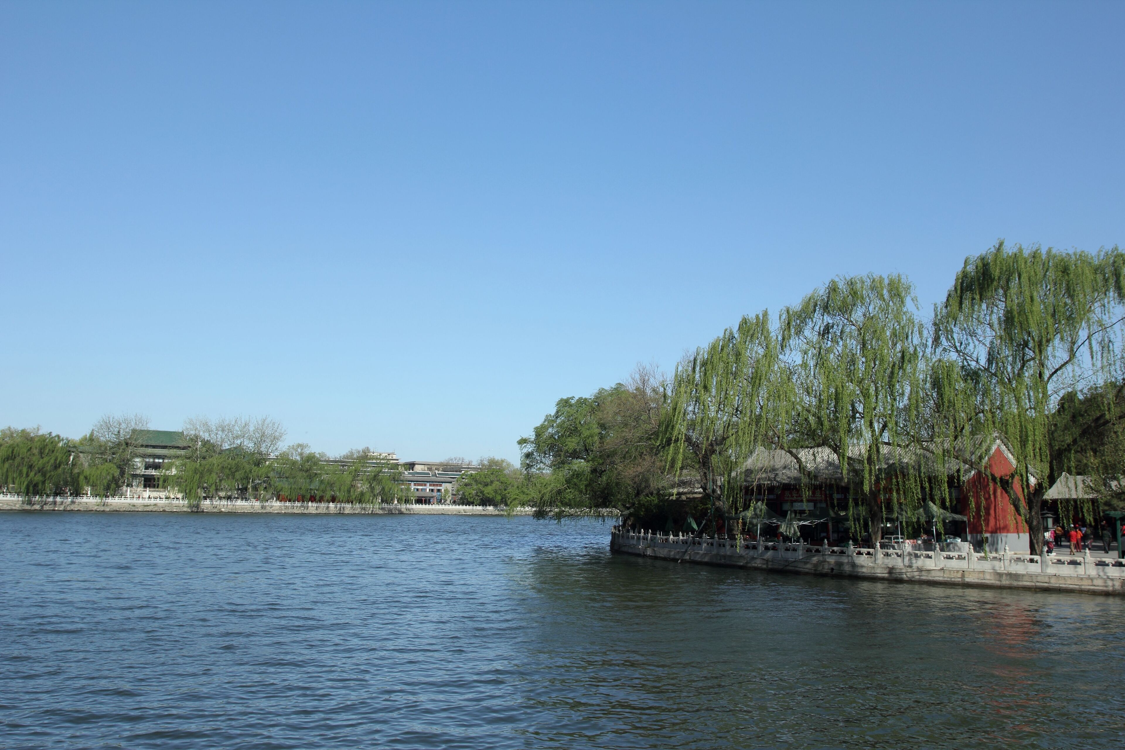 A calm lake with a traditional building and trees along the shore.