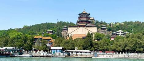 A traditional Chinese pagoda with multiple tiers, surrounded by lush greenery and a body of water in the foreground.