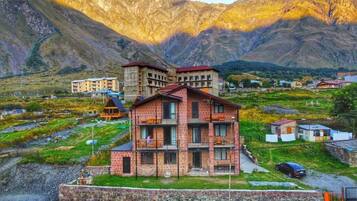A multi-story building with balconies, surrounded by a mountainous landscape.