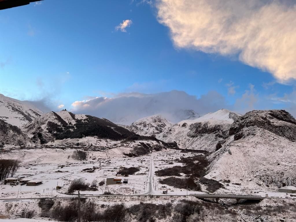 Un paisaje montañoso nevado con una carretera y edificios.
