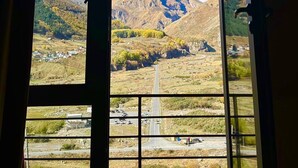 Una habitación con un ventanal amplio que ofrece vistas a una cordillera y una carretera debajo.