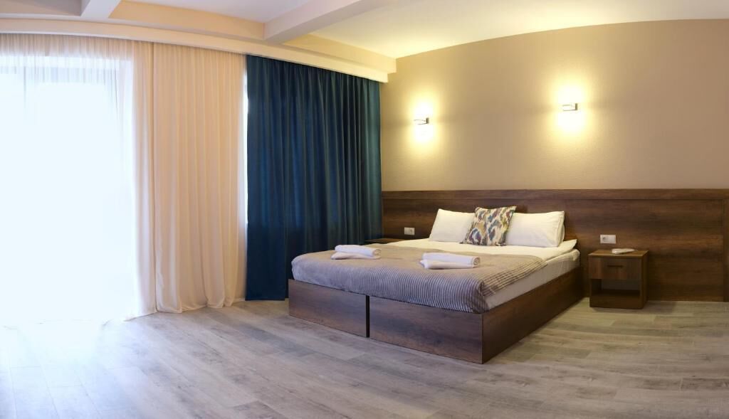 Una habitación de hotel con una cama grande, una mesita de noche y una lámpara fijada en la pared.