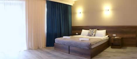 Una habitación de hotel con una cama grande, una mesita de noche y una lámpara fijada en la pared.