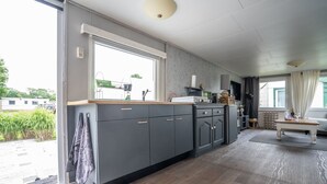 A modern kitchen with grey cabinets, a wooden countertop, and a large window. - Modern chalet on the Wadden Sea, near the beach (Westerland)