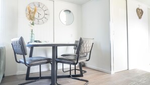 A dining area with a table and chairs, a wall clock, a mirror, and a heart-shaped decoration. - Modern chalet on the Wadden Sea, near the beach (Westerland)