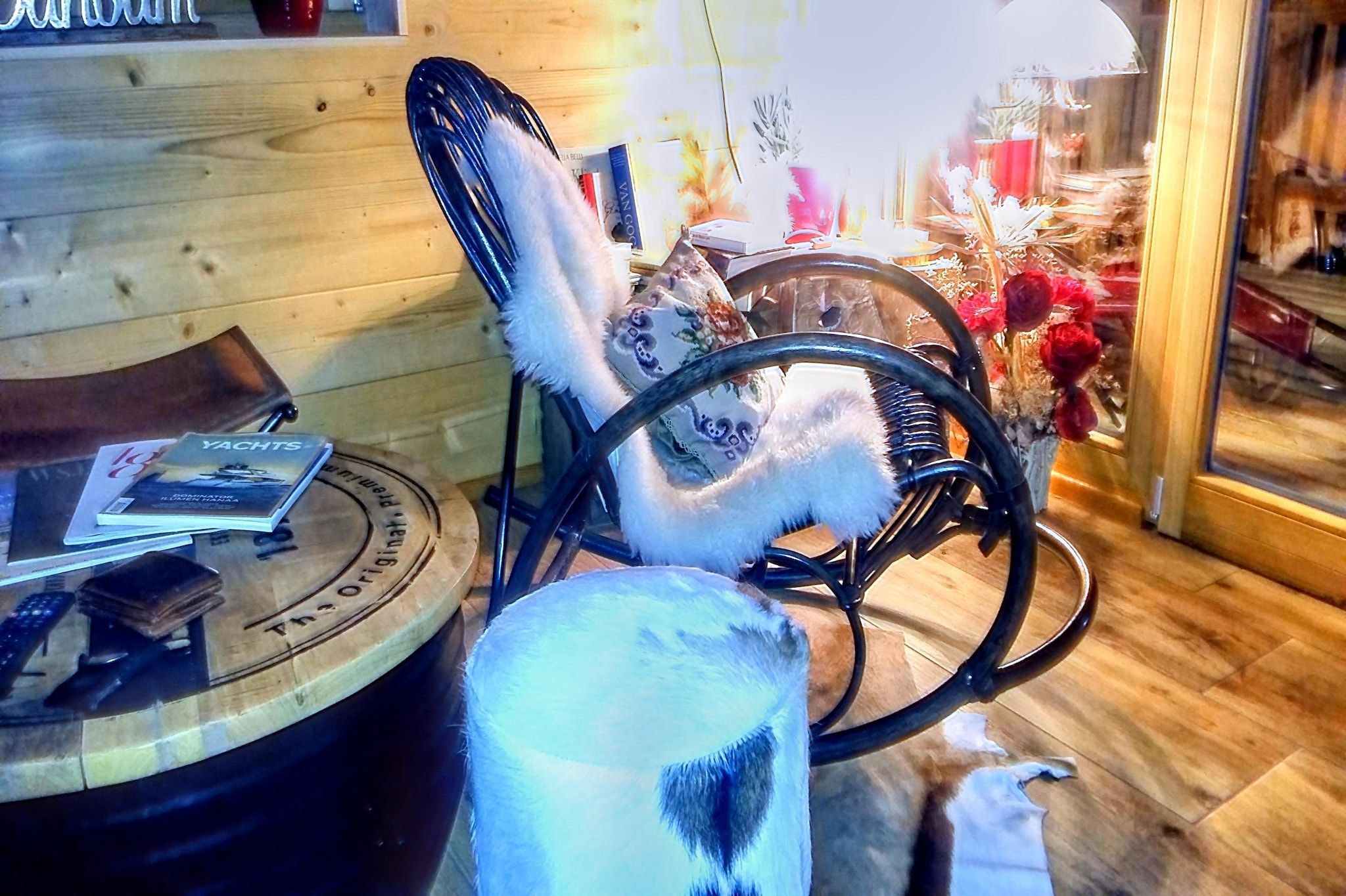 Un intérieur en bois avec une table ronde, une chaise et un vase rempli de fleurs.