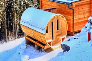 Eine Holz-Sauna mit Sitzbank im Inneren, umgeben von Schnee.