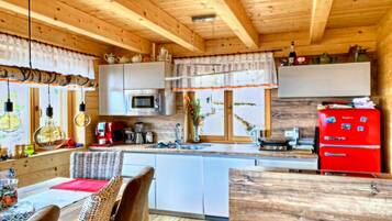 Ein Holzblockhaus-Interieur mit Küche, Essbereich und einem großen Holztisch.