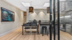 A modern kitchen with a central island, bar stools, and pendant lighting. - North Fremantle Cottage (North Fremantle)