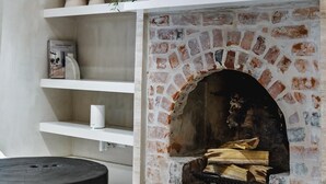 A modern interior with a brick fireplace, white shelves, and a potted plant. - North Fremantle Cottage (North Fremantle)