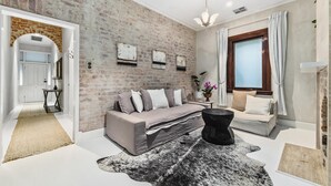 A modern living room with a brick wall, a sofa, a coffee table, and a large rug. - North Fremantle Cottage (North Fremantle)