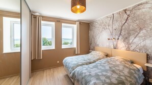 Ein Schlafzimmer mit einem Bett, zwei Fenstern, einer Marmorwand und einer Deckenleuchte.
