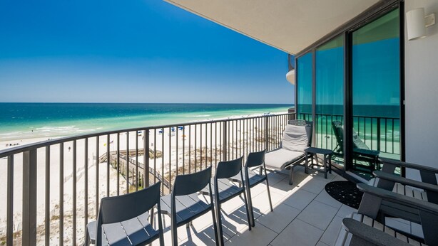 A balcony with a view of the beach and ocean.