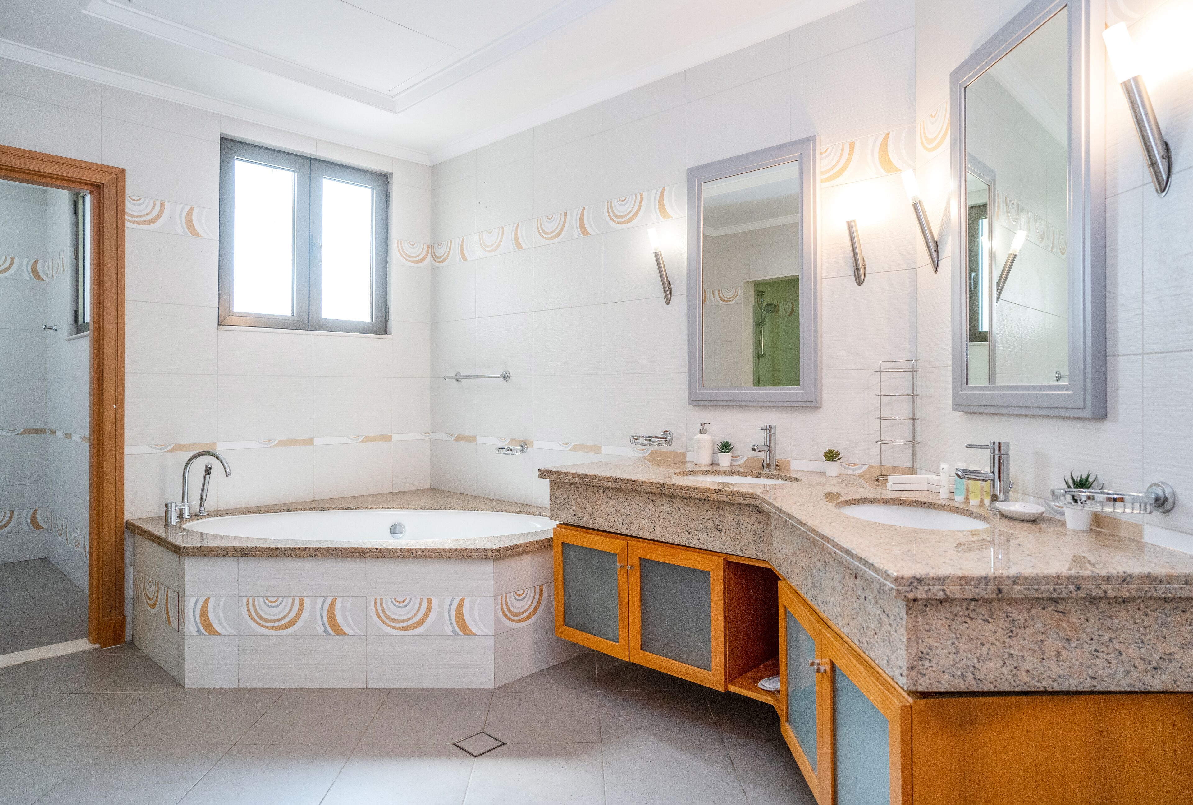 Een moderne badkamer met een vrijstaand bad, twee wasbakken en een grote spiegel.