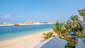 A beachfront property with a view of the ocean, a sandy beach, and a palm tree-lined patio. - 5BR Beach & pool villa in Palm (Dubai)