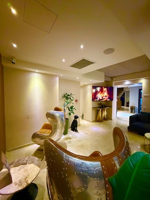 Una sala de estar moderna con un televisor grande, una estatua de perro y un diseño de silla único.