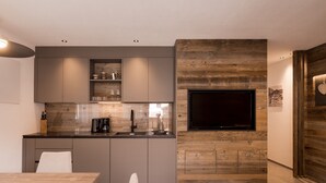 Eine moderne Küche mit integriertem Fernseher, Holzvertäfelung und einem Essbereich mit Tisch und Stühlen.