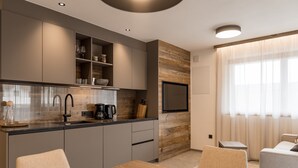 A modern kitchen with grey cabinets, a wooden accent wall, a built-in TV, and a dining area with a table and chairs.