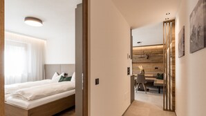Ett modernt hotellrum med en säng i trä, ett skrivbord och en matplats.