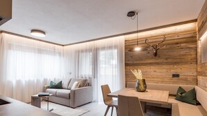 Ett modernt vardagsrum med en soffa, ett matbord och stolar, träpanel på väggarna och ett upphängt hjorthuvud.