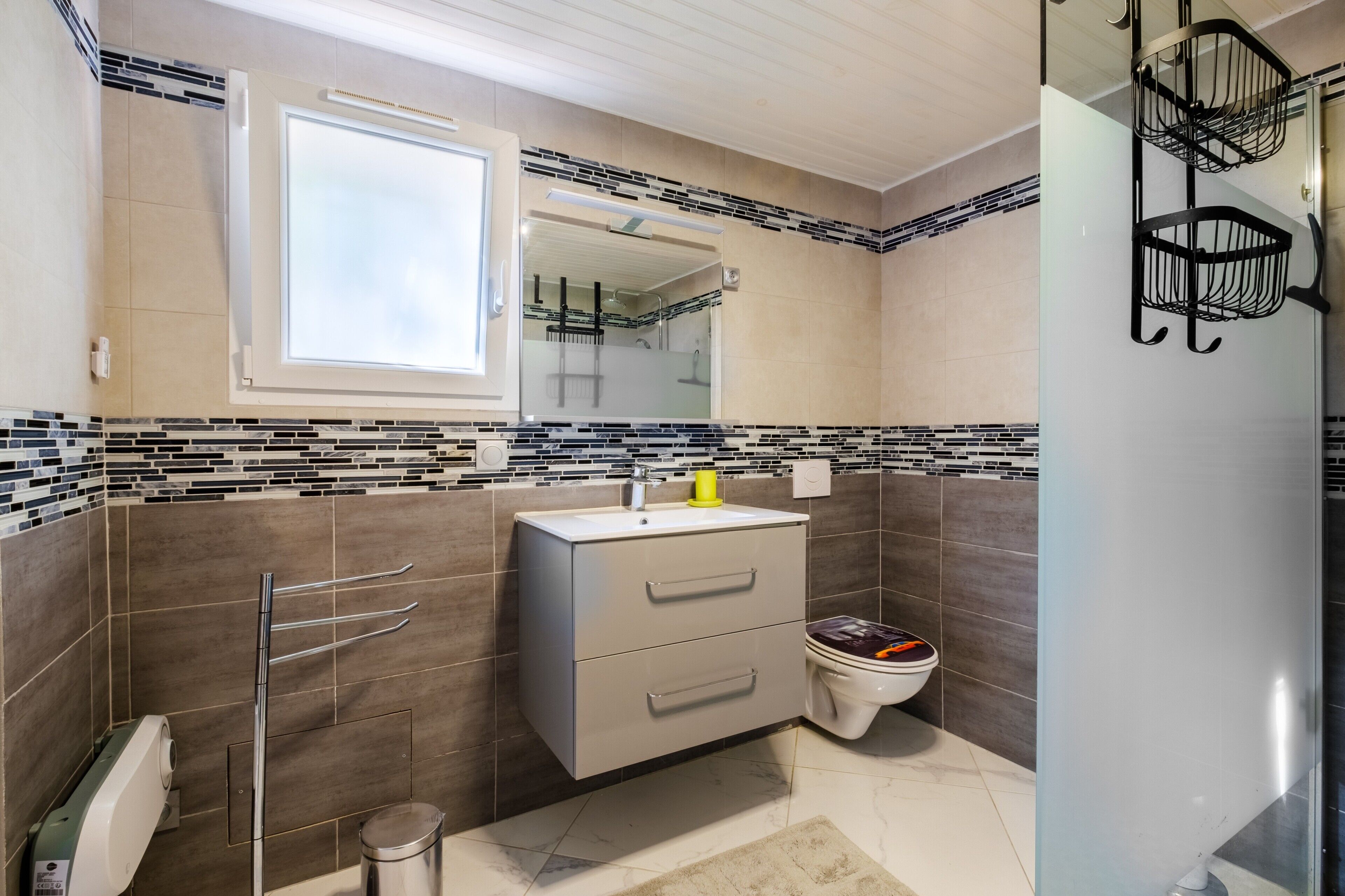 Une salle de bain avec un meuble-lavabo moderne, des toilettes, un miroir et une fenêtre.