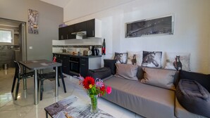 Un salon moderne comprenant un canapé, une table à manger et un coin cuisine.
