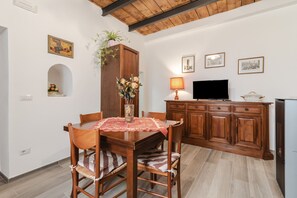 Un comedor con una mesa y sillas de madera, un armario con una planta y un televisor sobre un mueble de madera.