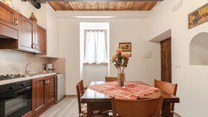 A dining area with a wooden table, chairs, and a vase of flowers. - Holiday Home 'Casa Pifaro' in Monterchi (Monterchi)