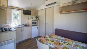 Una cuina compacta amb microones, fogó i rentatge, un frigorífic petit, i una zona de menjador amb taula i cadires.