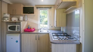 A compact kitchen with a microwave, coffee maker, sink, and stove. - 2ème mobilhome tout confort (Taglio-Isolaccio)