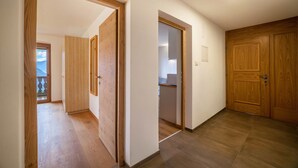 A hallway with wooden doors, a kitchen area, and a view of the outdoors. - Apartment 'Fichtenhof Edelweiss' with Mountain View, Shared Garden and Wi-Fi (Tarces)