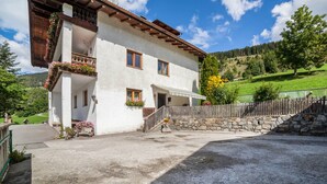 A two-story building with a balcony, a stone wall, and a wooden fence. - Apartment 'Fichtenhof Edelweiss' with Mountain View, Shared Garden and Wi-Fi (Tarces)