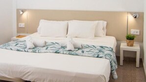 Een netjes ingerichte hotelkamer met een bed, nachtkastjes, een kleine potplant en een plafondlamp.