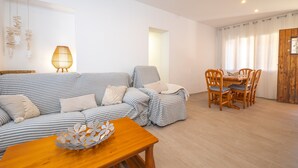 Ein Wohnzimmer mit einer Couch, einem Holztisch, einem Esstisch mit Stühlen und einer Lampe.