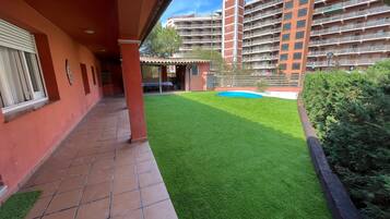 Une cour avec une pelouse artificielle, une petite piscine et un bâtiment doté de plusieurs balcons.