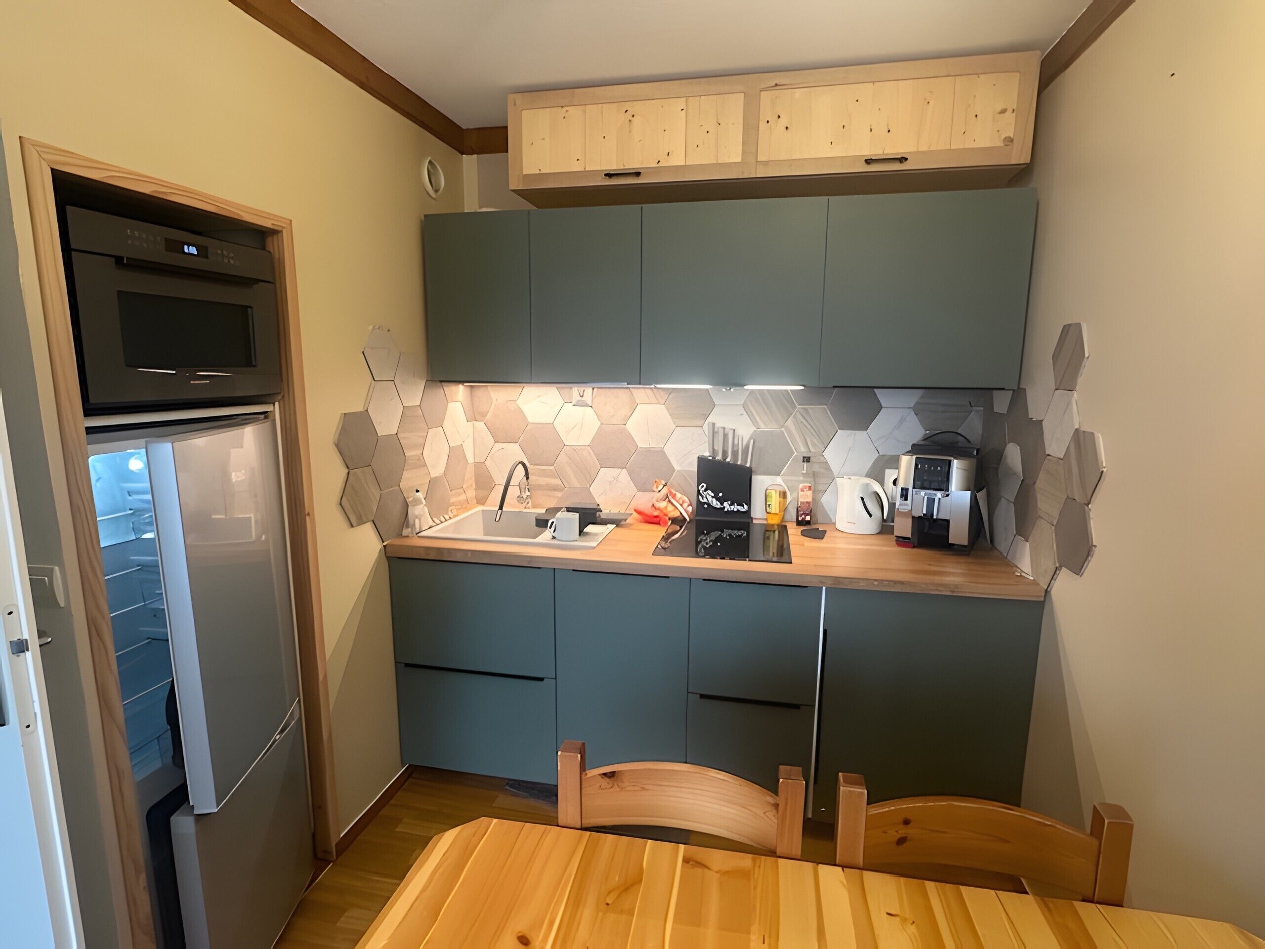 A compact kitchen with a built-in oven, a sink, and a coffee maker.
