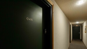 Ein Flur mit einer Tür, auf der '048' steht, und einer Deckenleuchte.