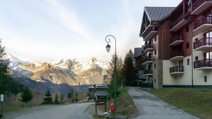 Ein Hotel mit Blick auf die Berge, mit Balkonen, einer Straßenlaterne und wolkenlosem Himmel.